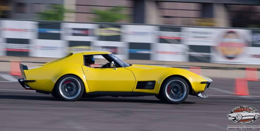A yellow sports car driving on a track.