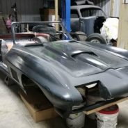 A black sports car is being worked on in a garage.