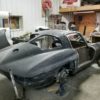 A black sports car in a garage is being worked on.