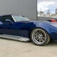 A blue chevrolet corvette parked in front of a garage.