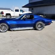 A blue corvette parked in front of a building.