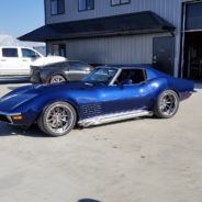 A blue corvette parked in front of a garage.