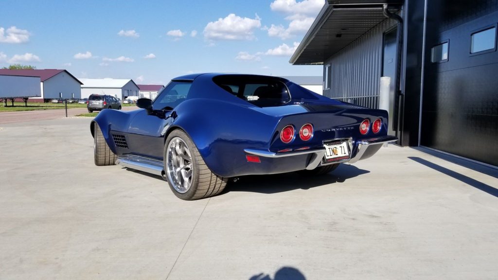 A blue corvette parked in front of a garage.