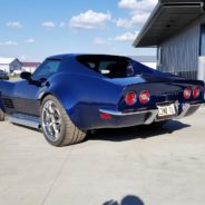 A blue corvette parked in front of a garage.