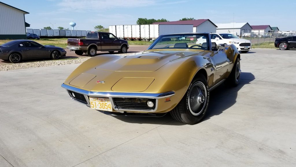 A gold corvette parked in a parking lot.