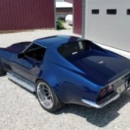 A blue corvette parked in front of a garage.