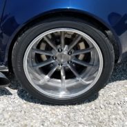 A close up of a blue car with a chrome rim.