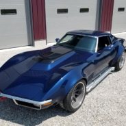 A blue chevrolet corvette parked in front of a garage.