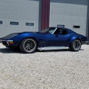 A blue chevrolet corvette parked in front of a garage.