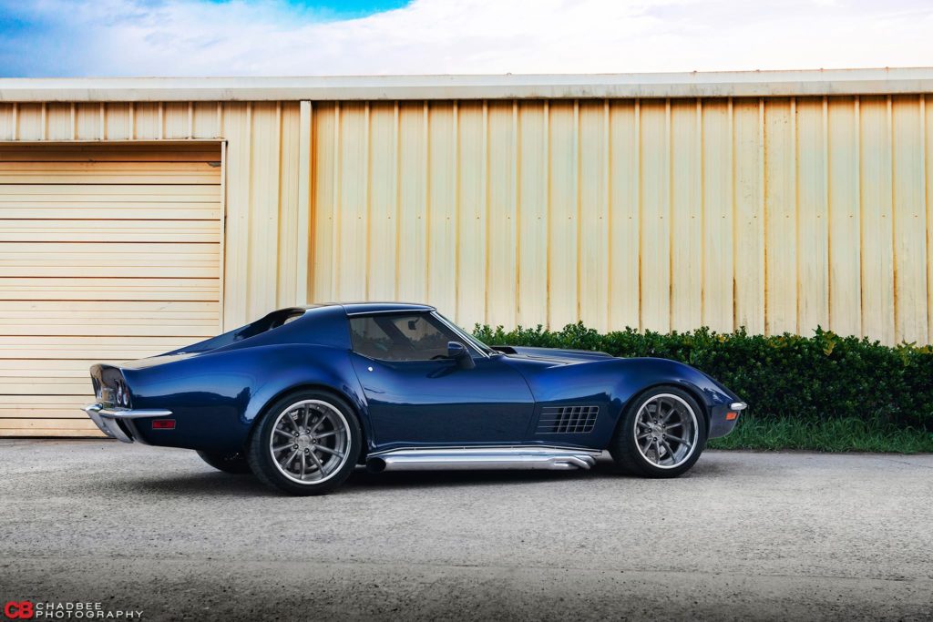 A blue chevrolet corvette parked in front of a garage.