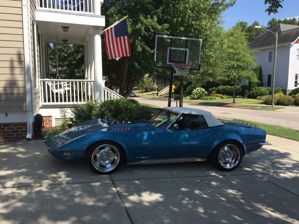 blue corvette with white top parked near house