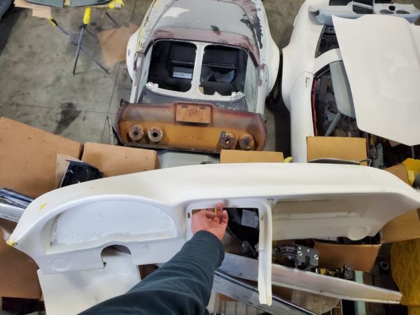 A man is working on a C3 CORVETTE CUSTOM DASH (Speedvette styled) in a garage.