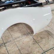 A 1968-1972 CORVETTE 3" X 4" FLARED FENDERS FACTORY WHEEL EDGE on a wooden floor.