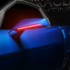 The 2005-2013 C6 CORVETTE ORACLE SMD CONCEPT SIDE MIRRORS of a blue car is illuminated with a red light.