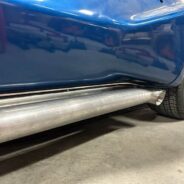 A close up of a blue car with C2/C3 CORVETTE LS SWAP STAINLESS STEEL SIDE EXIT HEADERS - MILL FINISH exhaust pipes.