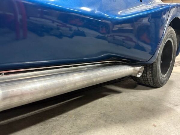 A close up of a blue car with C2/C3 CORVETTE LS SWAP STAINLESS STEEL SIDE EXIT HEADERS - MILL FINISH exhaust pipes.