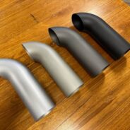 A group of C2/C3 CORVETTE LS SWAP STAINLESS STEEL SIDE EXIT HEADERS - CERAMIC FINISH on a table.