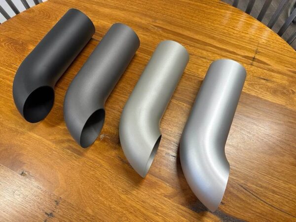 Four different types of C2/C3 CORVETTE LS SWAP STAINLESS STEEL SIDE EXIT HEADERS - CERAMIC FINISH on a wooden table.