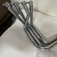 A set of C2/C3 CORVETTE LS SWAP STAINLESS STEEL SIDE EXIT HEADERS - POLISHED FINISH on a table.