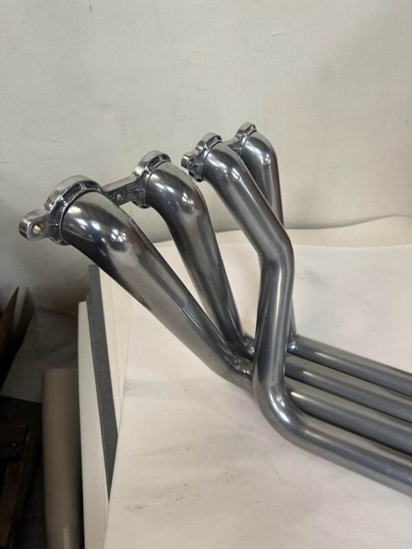 A pair of C2/C3 CORVETTE LS SWAP STAINLESS STEEL SIDE EXIT HEADERS - POLISHED FINISH on a table.