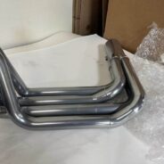 A pair of C2/C3 CORVETTE LS SWAP STAINLESS STEEL SIDE EXIT HEADERS - POLISHED FINISH on a table.