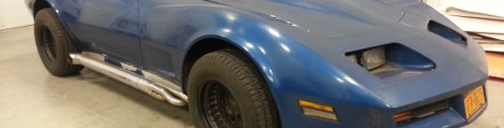 A blue chevrolet corvette parked in a garage.