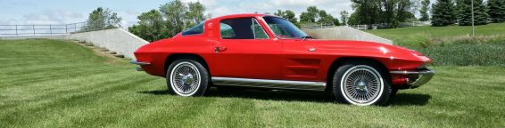 A red chevrolet corvette parked on a grassy field.